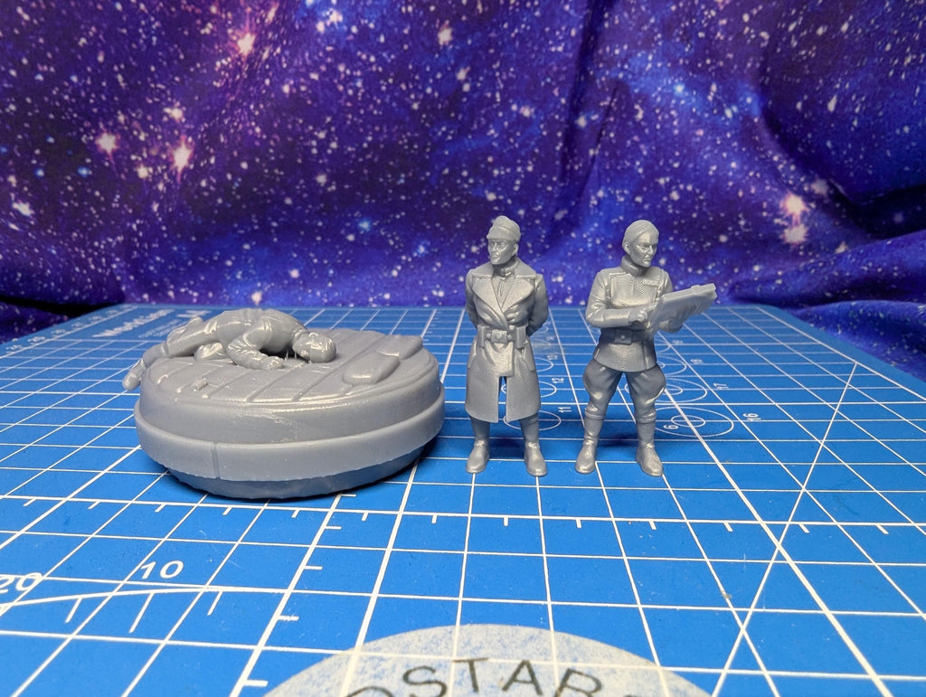 May include: Three gray miniature figurines on a blue grid surface. Two figures stand upright, one holding a tablet. The third figure is lying down on a circular platform. The background features a purple and blue galaxy design.