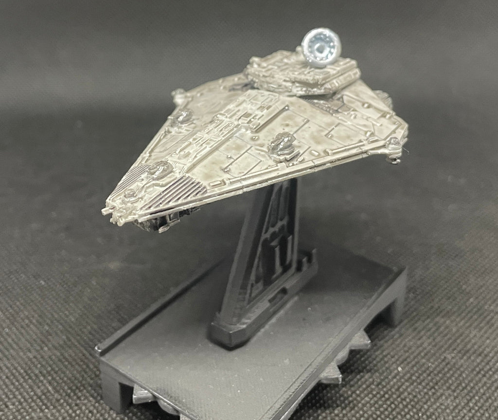 May include: A gray and silver spaceship model with a round, silver dome on top. The spaceship is on a black stand with a textured surface.