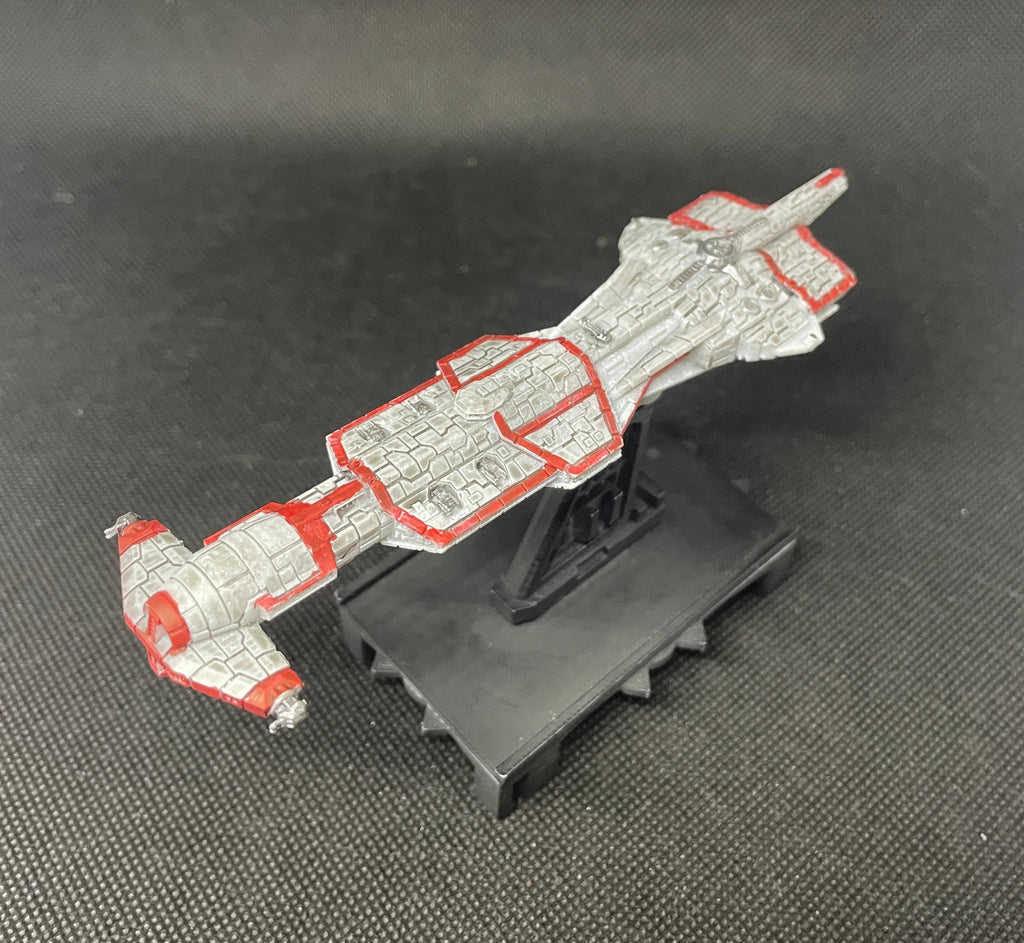 May include: A meticulously painted miniature spaceship model, predominantly white with red detailing, is displayed on a black stand. The spaceship's design features intricate, block-like textures and red lines outlining its form. The model is presented against a dark gray textured background, enhancing its visual appeal. This collectible miniature is perfect for enthusiasts of model spaceships and science fiction.
