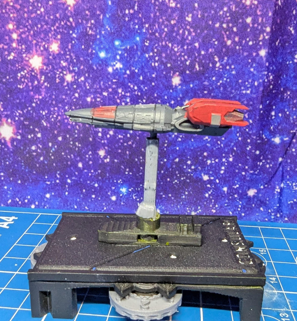 May include: A gray and red spaceship model on a black base with a gray stand. The spaceship has a red tail and a gray body. The base has a gear on the bottom and a small platform with a slot for the stand.
